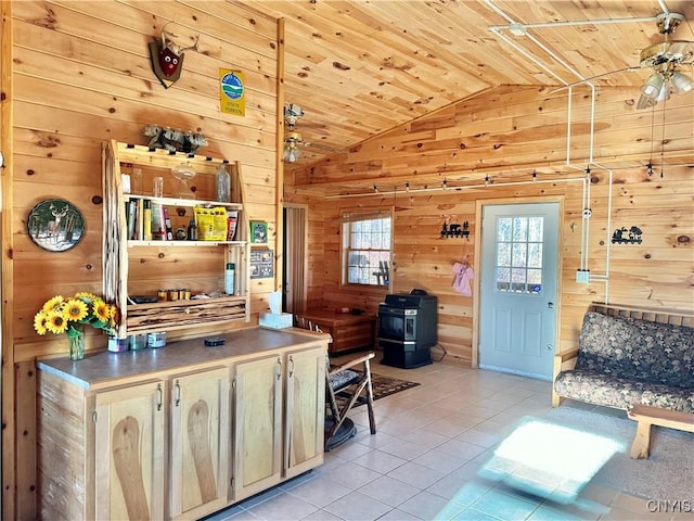 living room with a wood stove, lofted ceiling, wooden walls, light tile patterned floors, and wood ceiling