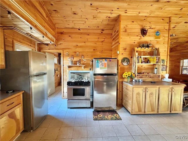 kitchen featuring wooden walls, light tile patterned floors, and appliances with stainless steel finishes