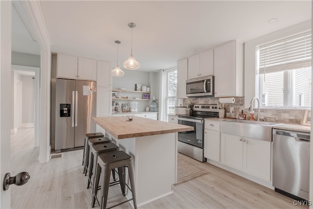 kitchen with white cabinets, stainless steel appliances, a kitchen island, and sink