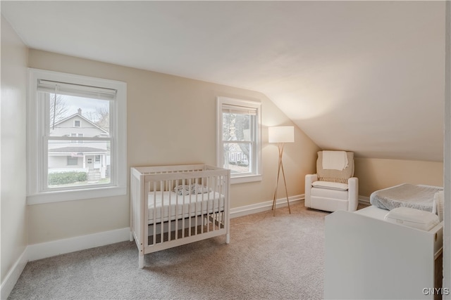 carpeted bedroom featuring lofted ceiling and a crib