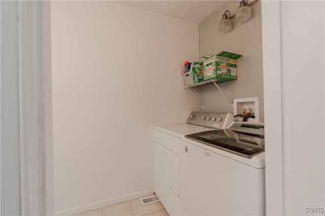 laundry area with washing machine and clothes dryer, light tile patterned floors, and a textured ceiling