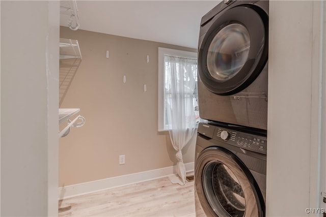 laundry area with stacked washer / dryer, a wealth of natural light, and light wood-type flooring