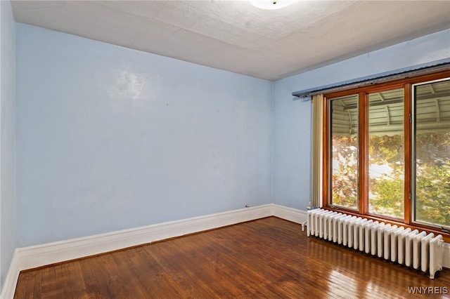 spare room with radiator, wood-type flooring, and a textured ceiling