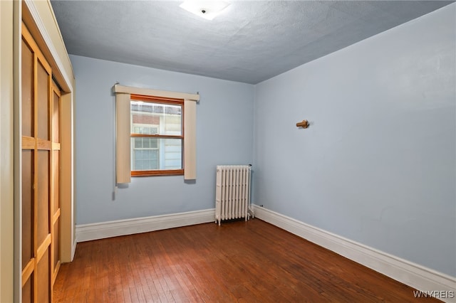 unfurnished bedroom featuring hardwood / wood-style flooring, radiator heating unit, a textured ceiling, and a closet