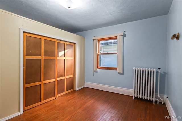 unfurnished room featuring radiator, dark hardwood / wood-style flooring, and a textured ceiling