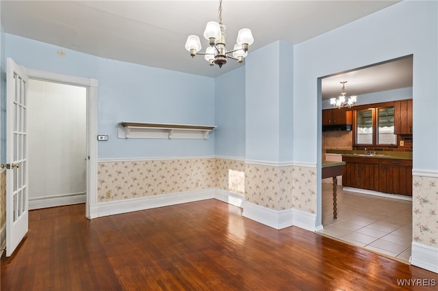 empty room with wood-type flooring, sink, and a chandelier