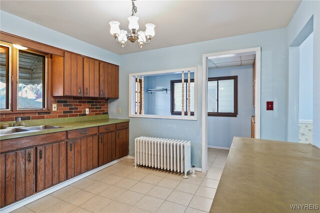 kitchen featuring radiator, sink, hanging light fixtures, a notable chandelier, and light tile patterned floors