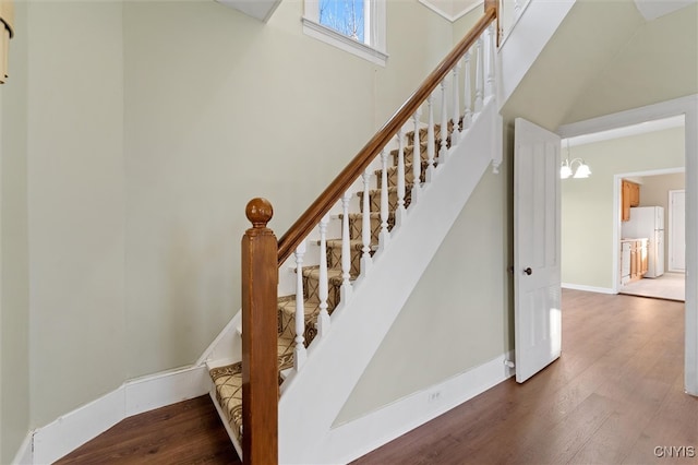 staircase with a chandelier and hardwood / wood-style floors