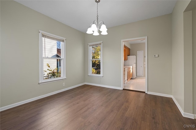 unfurnished dining area featuring dark wood-type flooring and a notable chandelier