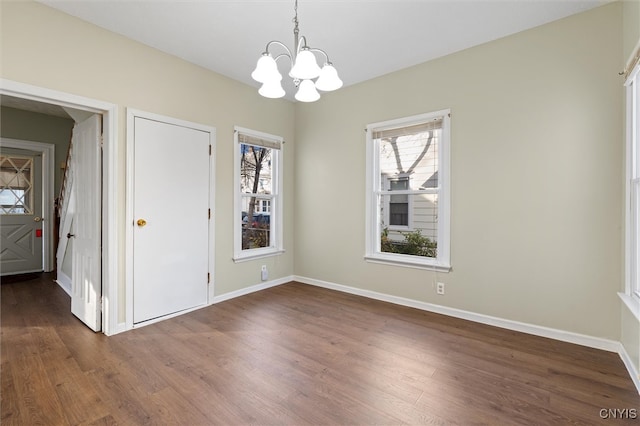 unfurnished dining area featuring a chandelier and dark wood-type flooring