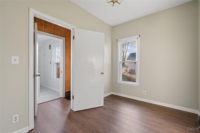 spare room featuring dark hardwood / wood-style flooring and lofted ceiling