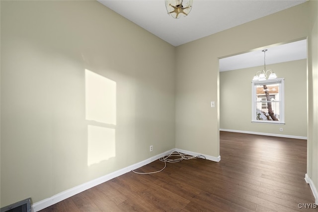 empty room with a chandelier and dark hardwood / wood-style floors