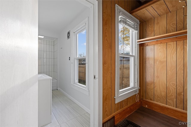 mudroom featuring wood walls, a healthy amount of sunlight, and light tile patterned floors