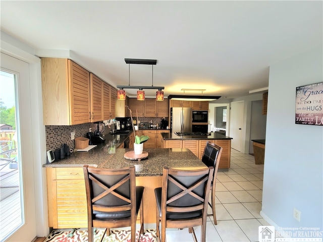 kitchen featuring hanging light fixtures, tasteful backsplash, stainless steel fridge, a kitchen bar, and light tile patterned floors