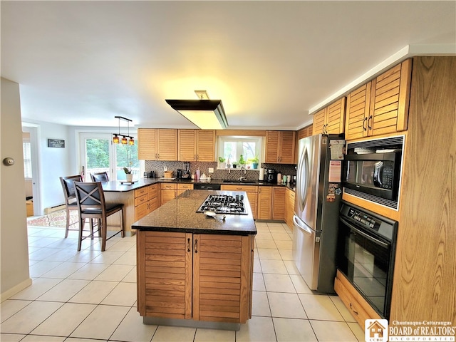 kitchen with decorative backsplash, black appliances, light tile patterned floors, decorative light fixtures, and a kitchen island