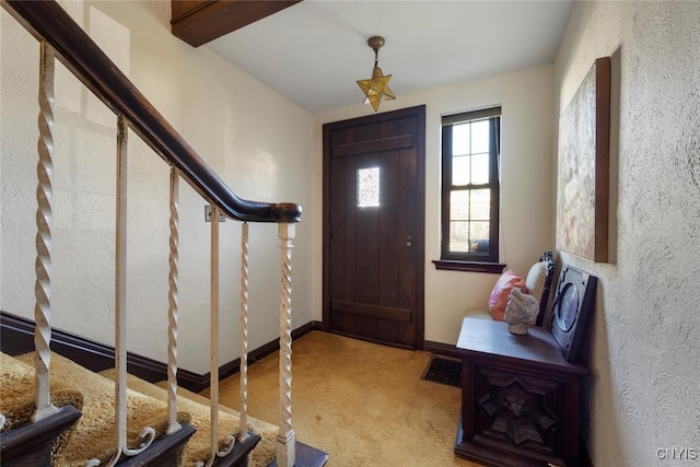 carpeted entryway with beamed ceiling