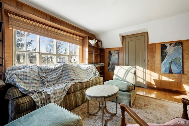 living area featuring hardwood / wood-style floors, lofted ceiling, and wooden walls