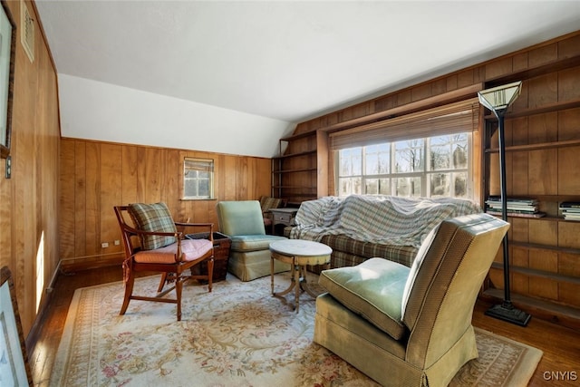 living area with a wealth of natural light, wood walls, light hardwood / wood-style floors, and vaulted ceiling