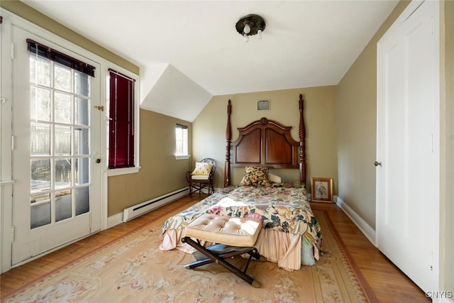 bedroom with multiple windows, light wood-type flooring, lofted ceiling, and a baseboard heating unit