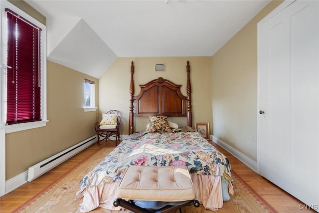 bedroom with light hardwood / wood-style flooring, a baseboard radiator, and vaulted ceiling