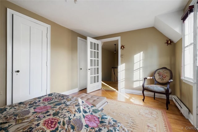 bedroom featuring baseboard heating, multiple windows, and light wood-type flooring