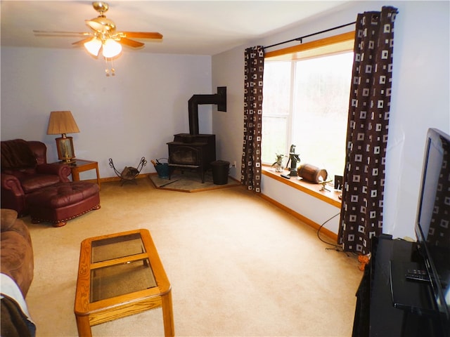 living room featuring a wood stove, ceiling fan, and carpet floors