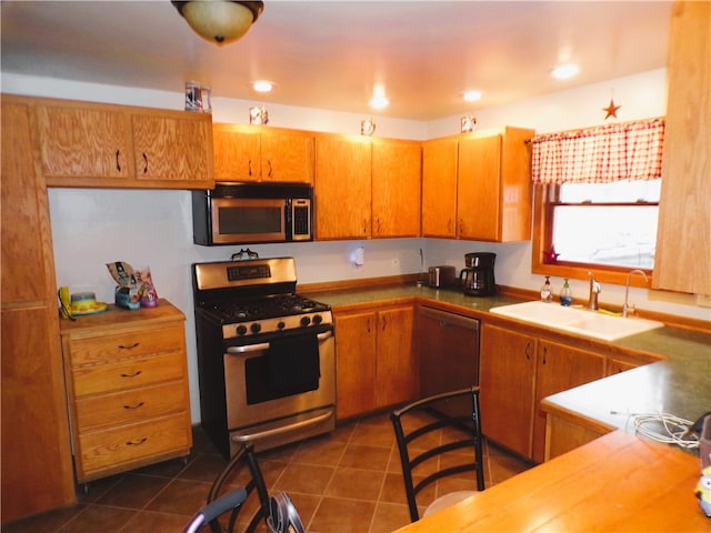 kitchen featuring sink, dark tile patterned flooring, and appliances with stainless steel finishes