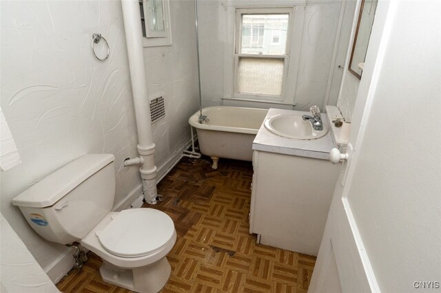 bathroom featuring vanity, toilet, parquet floors, and a tub