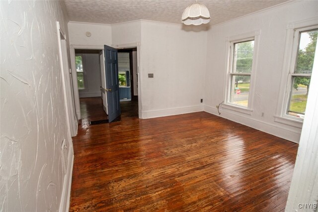 unfurnished room with a textured ceiling, crown molding, and dark wood-type flooring