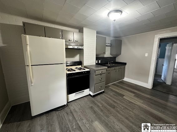 kitchen with gray cabinetry, sink, dark wood-type flooring, tasteful backsplash, and white appliances