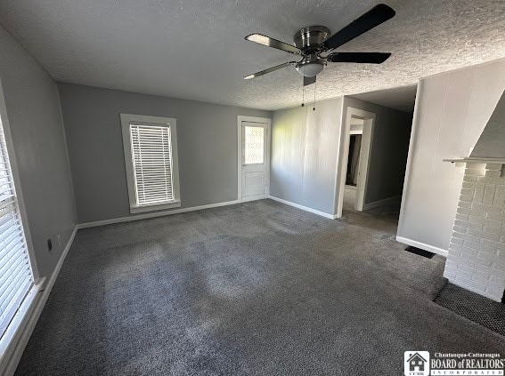 carpeted empty room featuring ceiling fan, a fireplace, and a textured ceiling