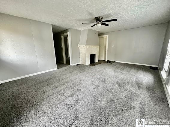 unfurnished living room with dark colored carpet, ceiling fan, a textured ceiling, and a brick fireplace