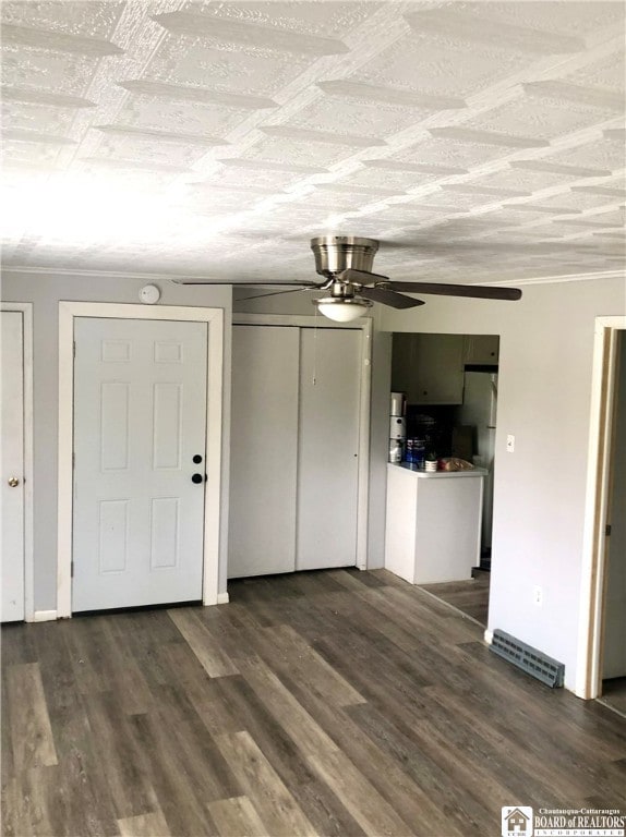 unfurnished living room with ceiling fan, dark hardwood / wood-style flooring, and ornamental molding