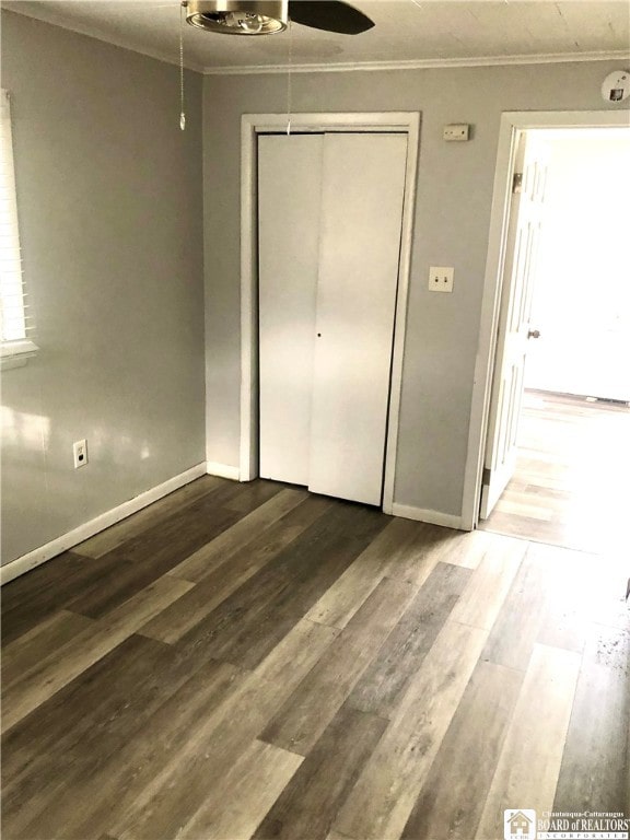 unfurnished bedroom with hardwood / wood-style flooring, ornamental molding, and a closet