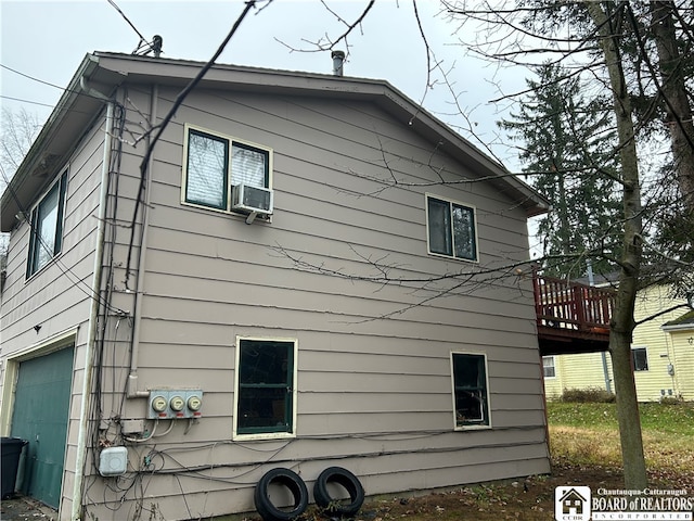 view of side of home with a garage, cooling unit, and a deck