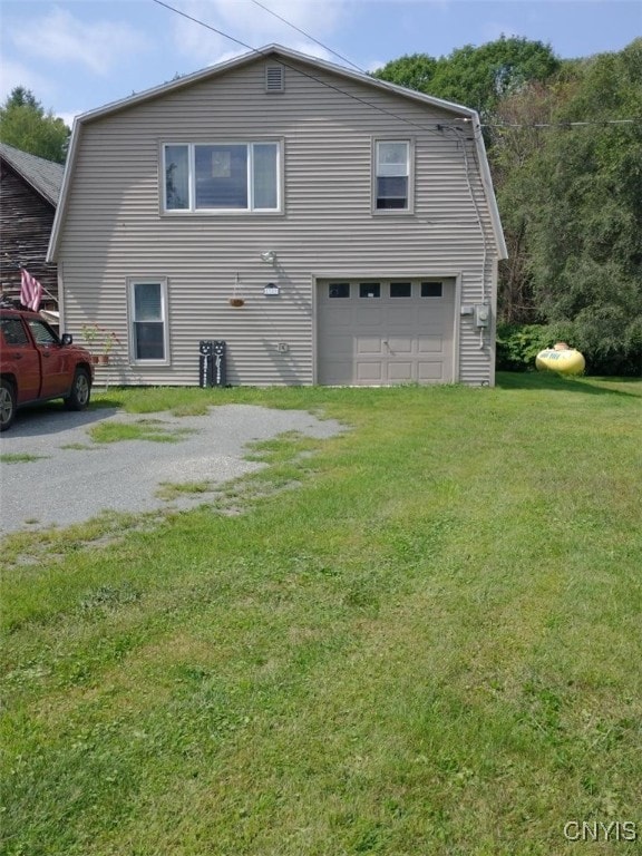 back of house featuring a garage and a lawn