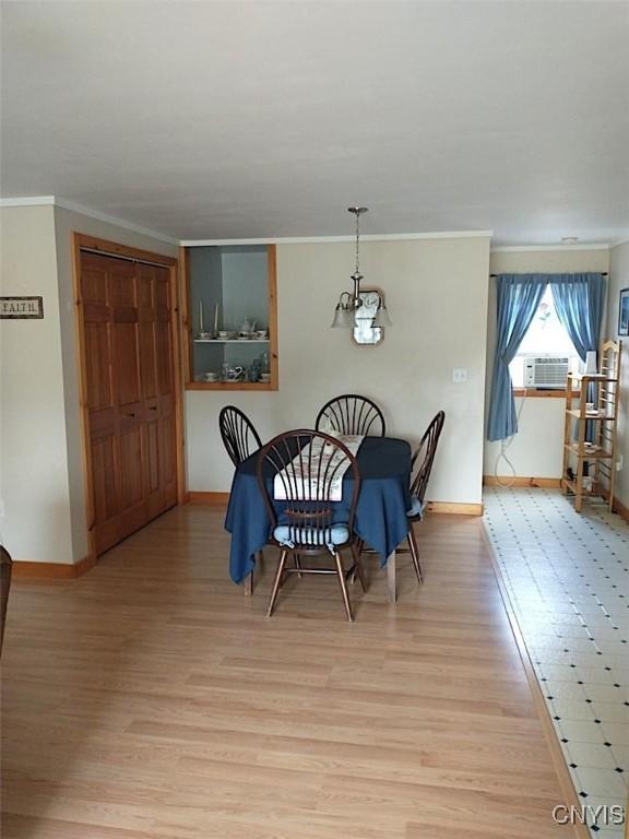 dining area featuring cooling unit, ornamental molding, a chandelier, and light wood-type flooring