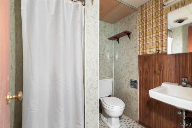 bathroom featuring tile patterned flooring, sink, toilet, and wood walls