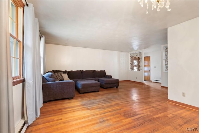 living room with light hardwood / wood-style floors, a baseboard radiator, and a notable chandelier