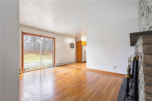 unfurnished living room with a fireplace, light hardwood / wood-style flooring, and a baseboard heating unit