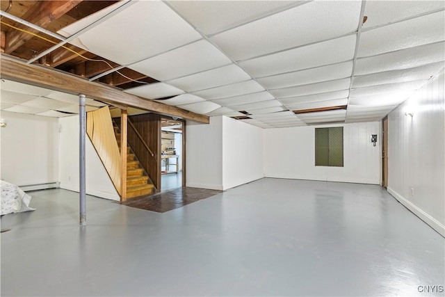 basement featuring a paneled ceiling and a baseboard radiator