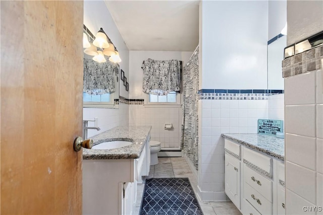 bathroom with tile patterned flooring, vanity, tile walls, and toilet