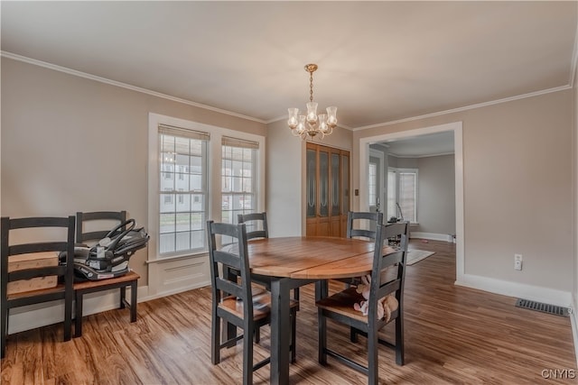 dining space with crown molding, wood-type flooring, and a notable chandelier