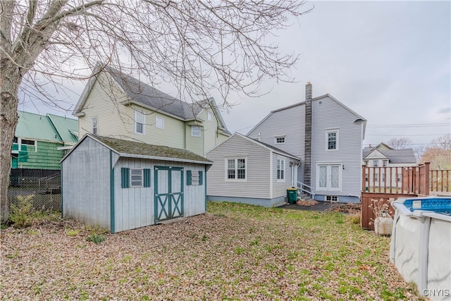 rear view of property featuring a pool side deck, a storage shed, and a yard