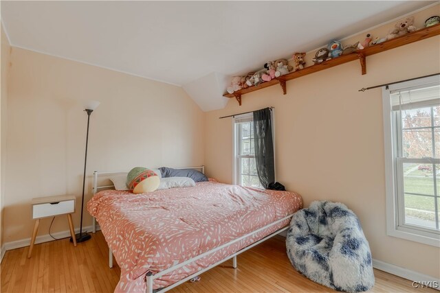 bedroom with hardwood / wood-style flooring, multiple windows, and lofted ceiling