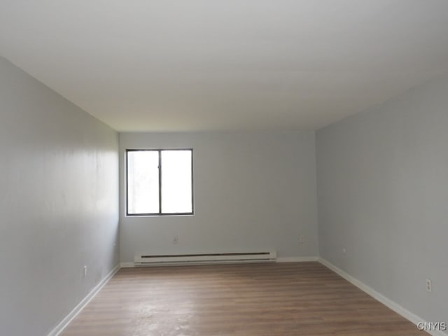 empty room with hardwood / wood-style floors and a baseboard radiator