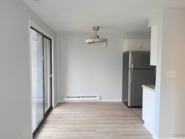 interior space featuring stainless steel refrigerator, white cabinets, light hardwood / wood-style floors, and a baseboard heating unit