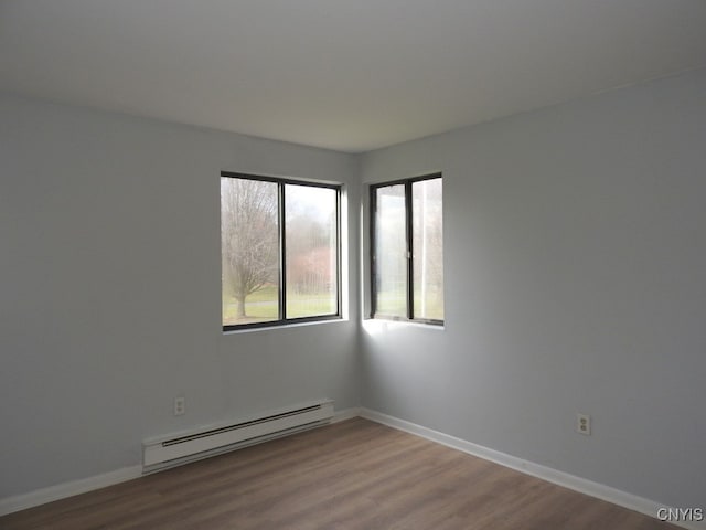 empty room with hardwood / wood-style flooring and a baseboard heating unit