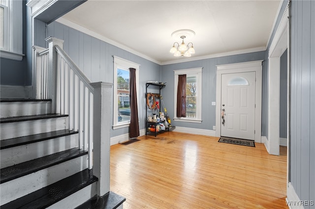 entryway with light hardwood / wood-style flooring, an inviting chandelier, and ornamental molding