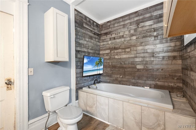 bathroom with tiled bath, toilet, and hardwood / wood-style flooring